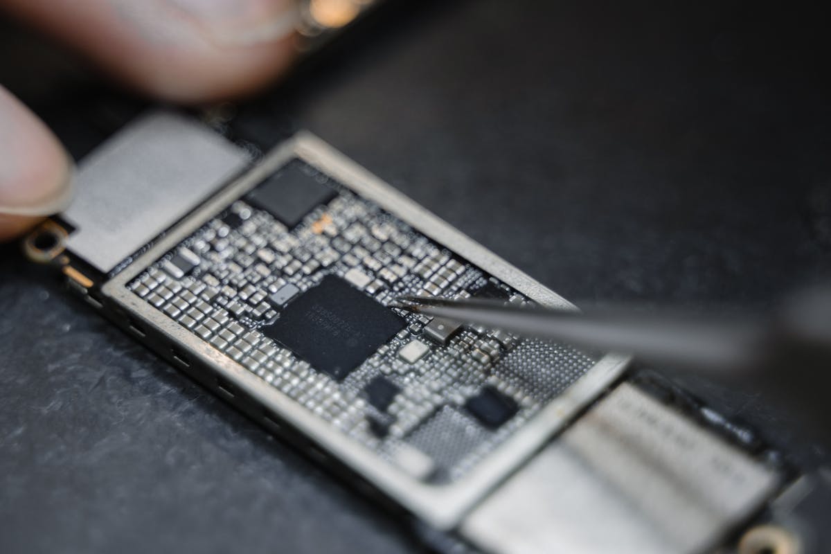 Microsoldadura de chip en placa base de móvil con pinzas de precisión